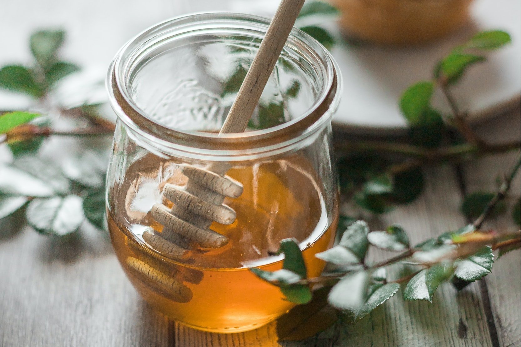 A close-up of a tea infuser containing black tea and lavender buds, sitting atop a glass teacup filled with deep red tea. Fresh lavender sprigs are placed beside the cup on a textured surface, highlighting the calming ambiance of herbal tea preparation.